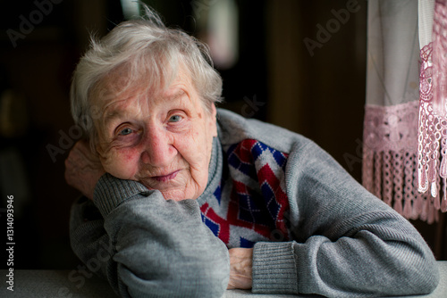 Obraz na płótnie A soulful close-up portrait of an elderly woman posing while seated at a table, capturing her wisdom and quiet strength. w salonie