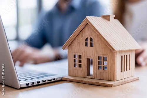 Wallpaper Mural A serene scene unfolds, a wooden miniature house taking center stage, symbolizing home and security A modern laptop, blurred yet present, hints at digital connectivity and remote work possibilities A Torontodigital.ca