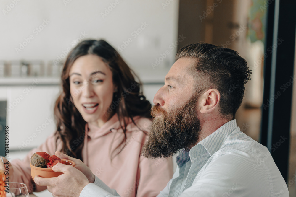 Bearded man holding bowl of meatballs with excited woman behind him Bearded man holding bowl of meatballs with excited woman behind him