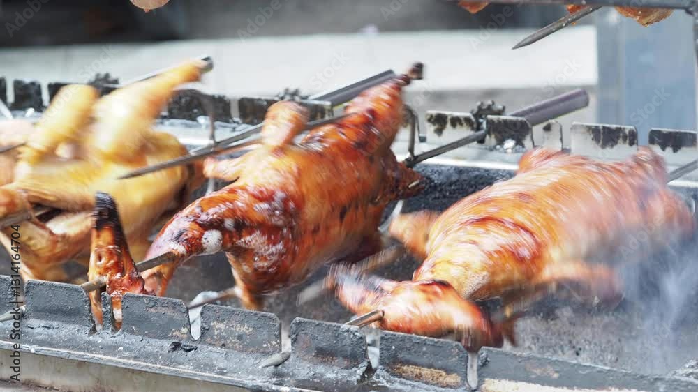 A close-up of ducks rotating on a grill, slowly roasting to a golden brown.