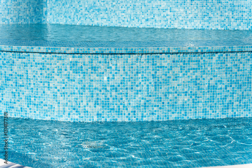 Overflowing water cascading down steps in a tranquil blue pool