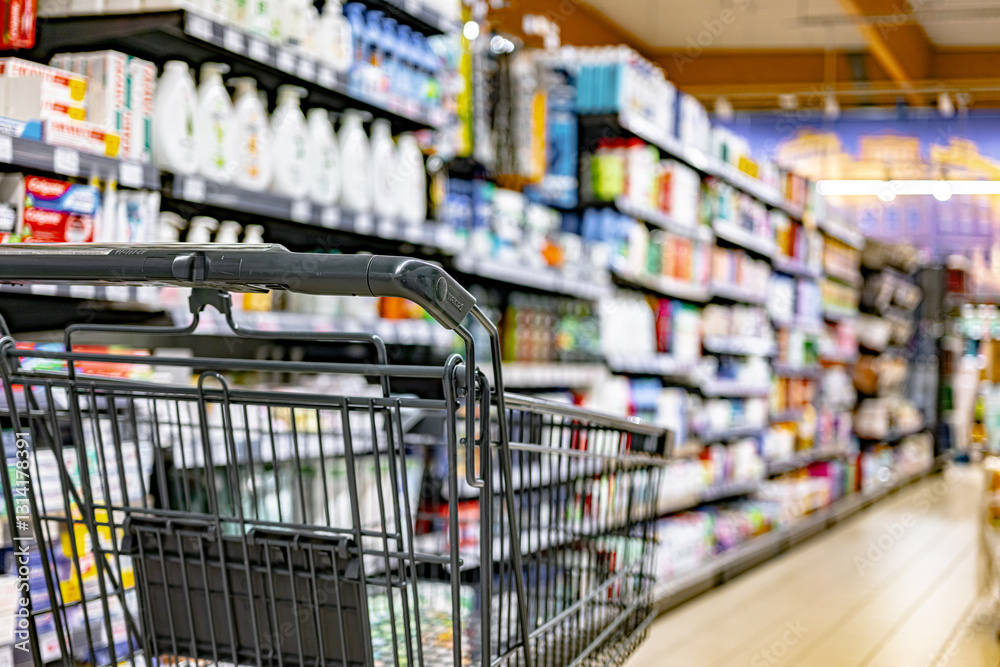 A shopping cart by a store shelf in a supermarket A shopping cart by a store shelf in a supermarket
