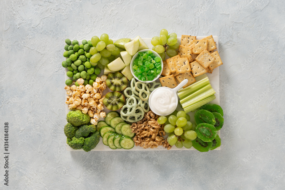 St Patricks day charcuterie board with green fruit and vegetables on light background. View from above. Festive holiday appetizer for celebration.
