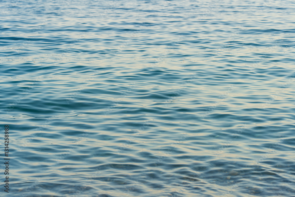Calm sea surface at dawn, gentle waves playing with sunlight, creating a serene atmosphere. Calm sea surface at dawn, gentle waves playing with sunlight, creating a serene atmosphere.