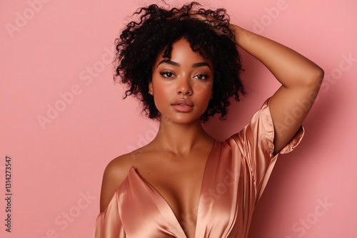 confident Black woman in silk blouse touching glowing skin against pink backdrop