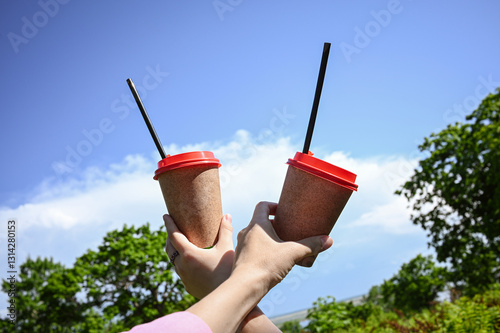 Coffee from a paper cup, relaxing in a sunny spring green city park in nature. Two cups. The concept of urban leisure.