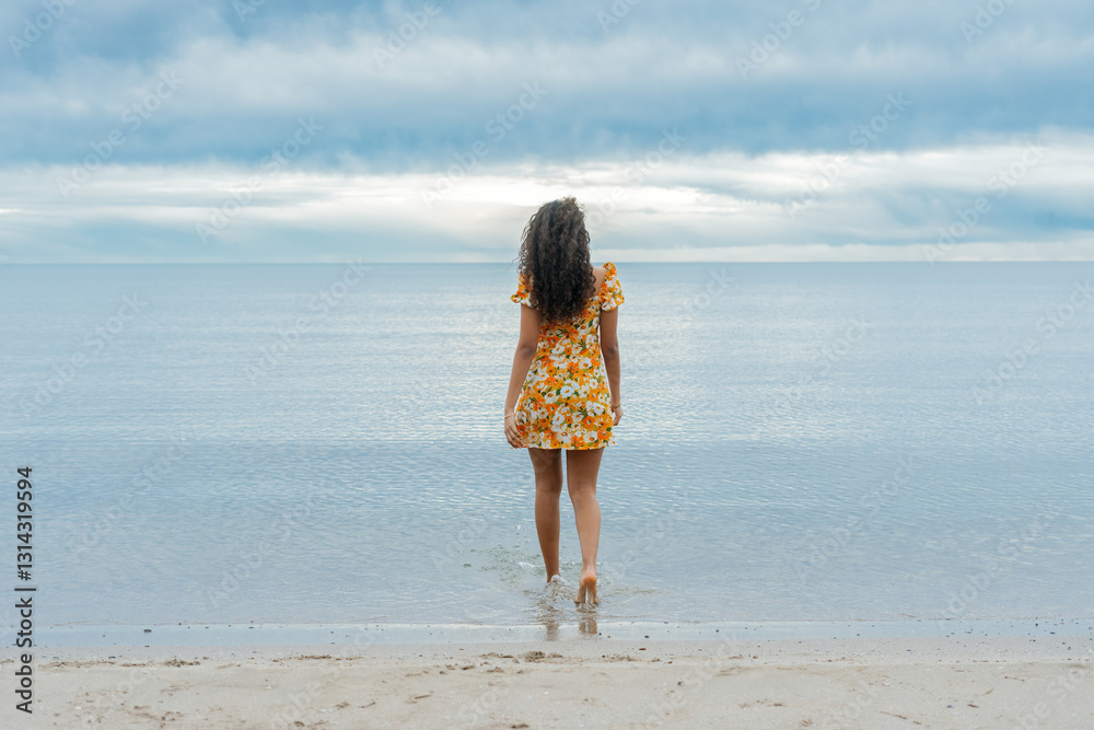 Young woman walking into the sea enjoying summer vacation Young woman walking into the sea enjoying summer vacation