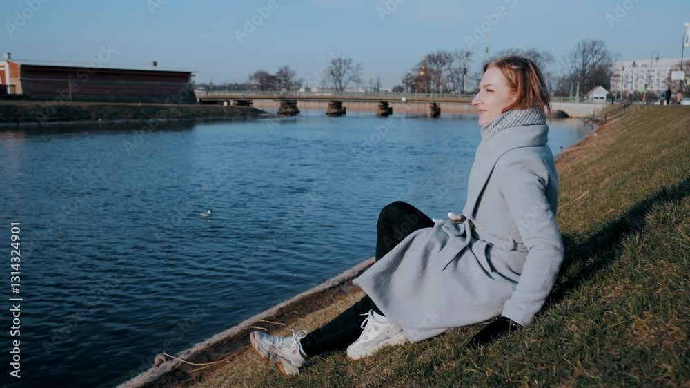 Woman enjoying sun by river throwing crumbs to birds Woman enjoying sun by river throwing crumbs to birds
