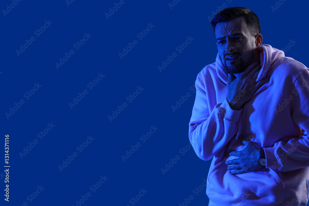 Fototapeta premium Young man having panic attack on blue background