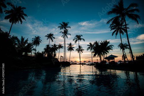 Obraz na płótnie A cozy tropical beach with palm silhouettes against a horizon where the sun sets, creating a serene and picturesque atmosphere. w salonie