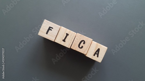 FICA acronym made of wooden letter cubes on dark background. Federal Insurance Contributions Act