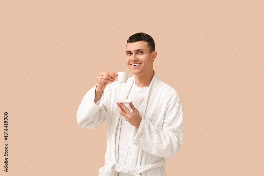 Handsome young man in bathrobe with cup of coffee on beige background Handsome young man in bathrobe with cup of coffee on beige background