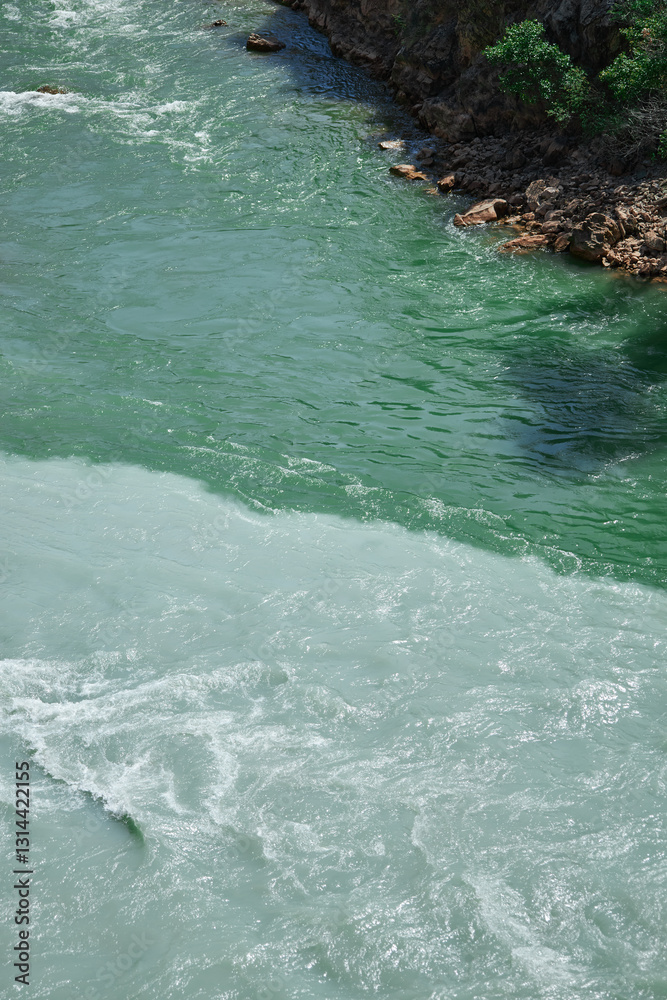 Obraz premium confluence of two rivers of different colors, emerald green and turquoise muddy water, riverside