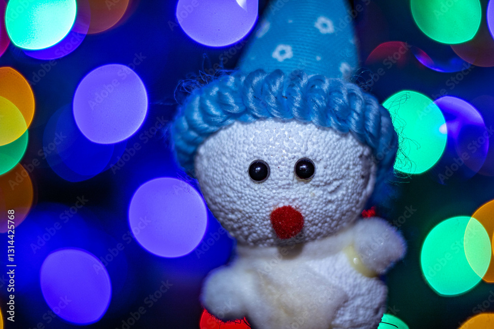 Fototapeta premium Very colorful illuminated Christmas decorations, in the shape of a snowman, with a blue hat and a background of blurred colored lights