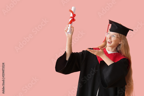 Female graduating student in mortar board pointing at diploma on pink background