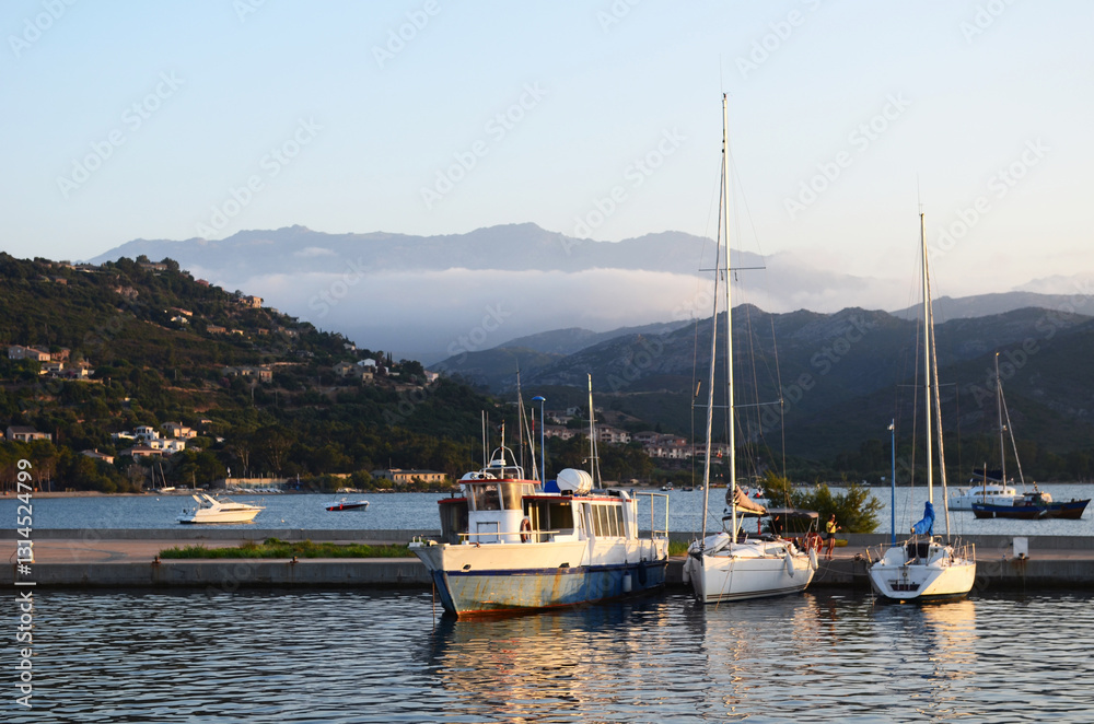 Boats and yachts in harbor with mountains and clouds at sunset Boats and yachts in harbor with mountains and clouds at sunset