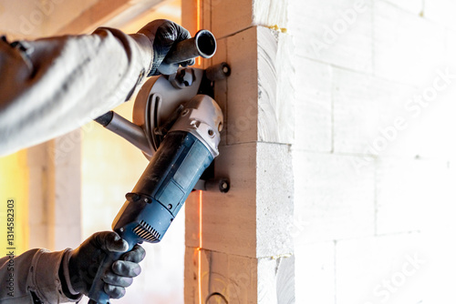 Construction worker cutting aerated concrete blocks with angle grinder