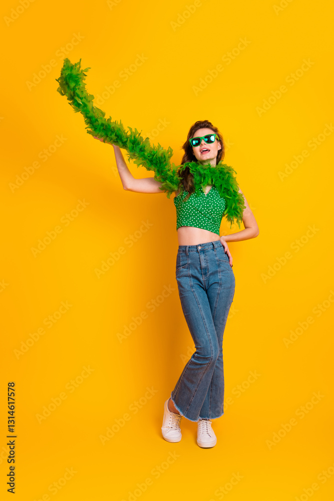 Stylish young woman wearing casual trendy outfit posing with green boa against vibrant yellow background, showcasing confidence and charm Stylish young woman wearing casual trendy outfit posing with green boa against vibrant yellow background, showcasing confidence and charm