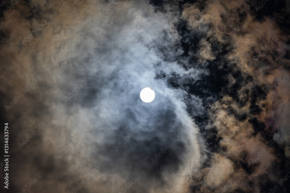 dettaglio di un eclissi solare parziale, di giorno, a inizio estate 2021 dall'Italia, con cielo nuvoloso