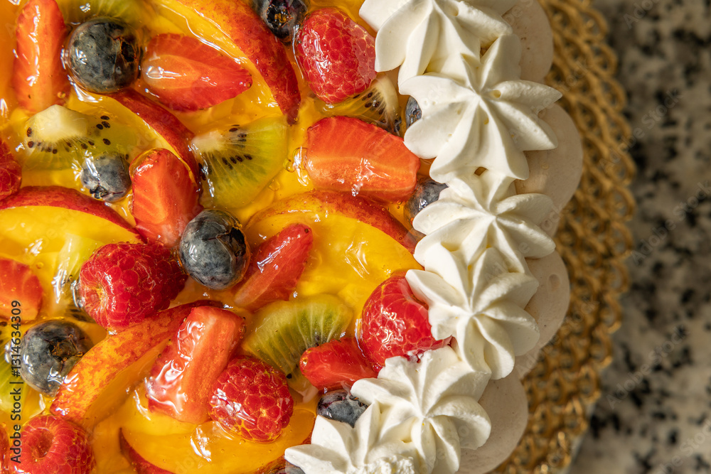dettaglio macro, da sopra, di una torta di crema e frutta, con pezzi di mirtilli neri, fragole, kiwi e pesche, decorata con crema e panna