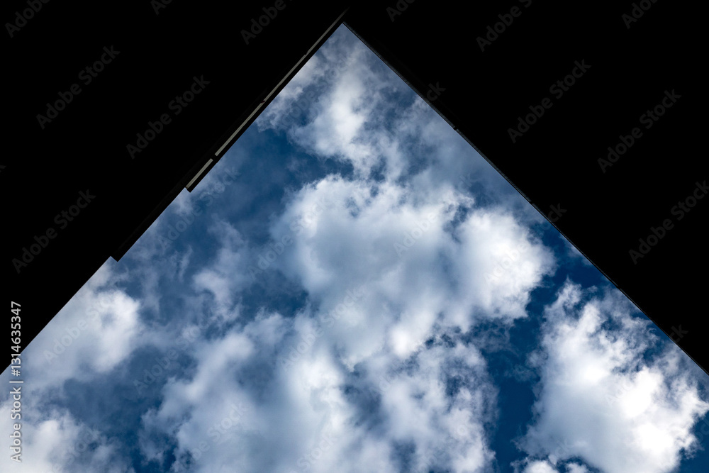 cornice parziale nera di forma triangolare che copre parte del cielo azzurro e nuvoloso, di giorno