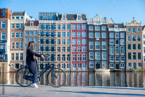 Φωτογραφία Une femme sur un vélo en face des maisons dansantes dans la ville de Amsterdam a
