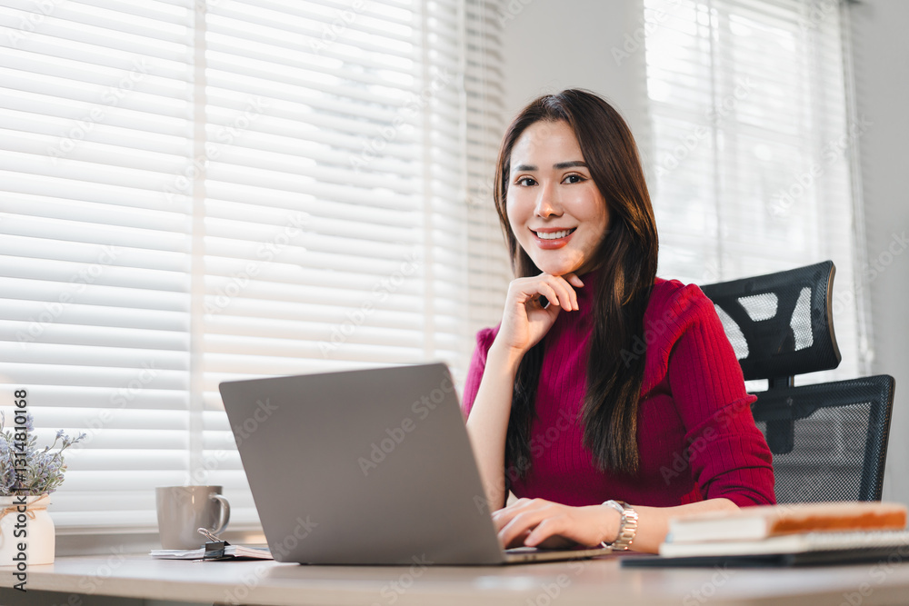 Confident Woman in Red Sweater Working on Laptop at Desk in Bright Office. Confident Woman in Red Sweater Working on Laptop at Desk in Bright Office.