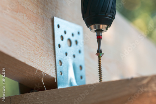 screwing a self-tapping screw into a wooden beam close-up