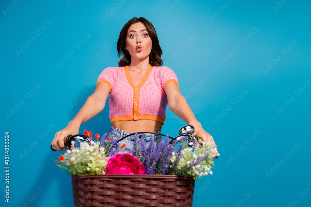 Stylish young woman on a colorful bicycle with flower basket posing against vibrant blue background Stylish young woman on a colorful bicycle with flower basket posing against vibrant blue background