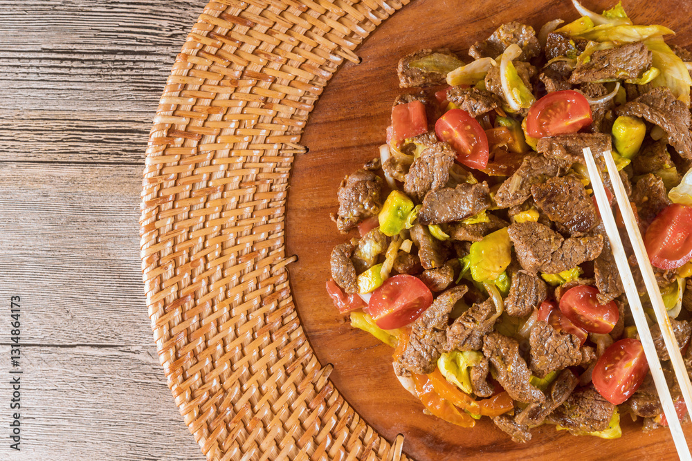 Asian cuisine tasty stir fried beef veggies are beautifully served on round wooden platter for delicious meal.
