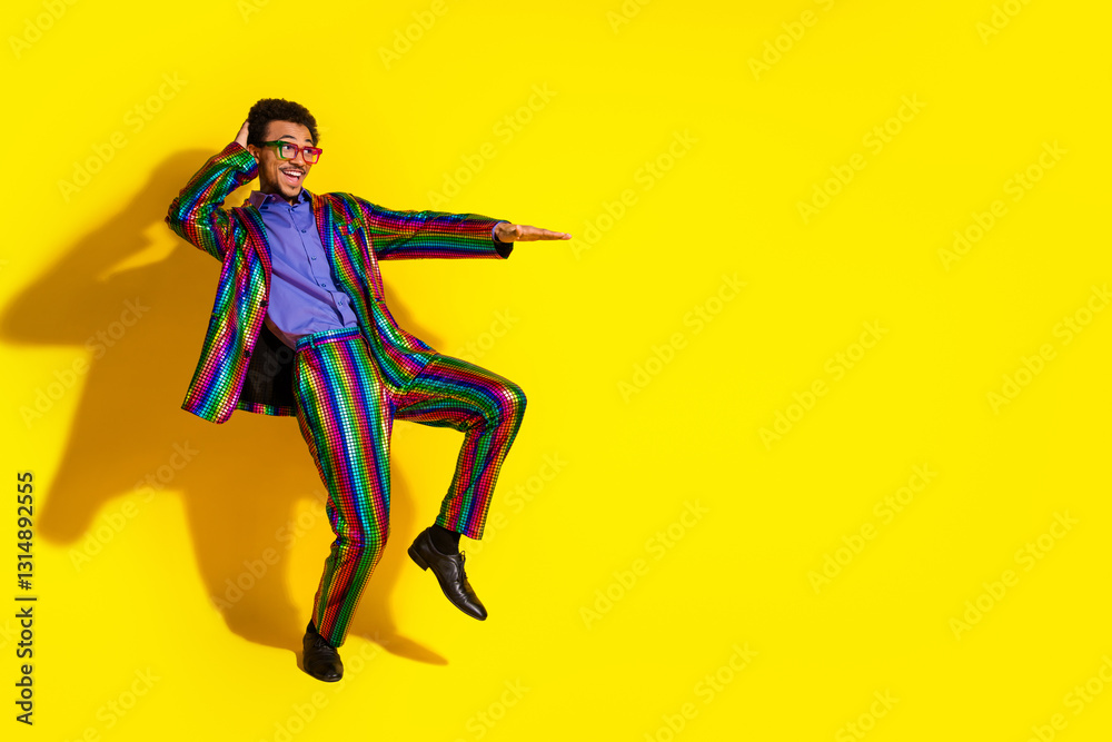 Colorful young man in striped retro suit dancing energetically against a solid yellow background, showcasing fun Colorful young man in striped retro suit dancing energetically against a solid yellow background, showcasing fun