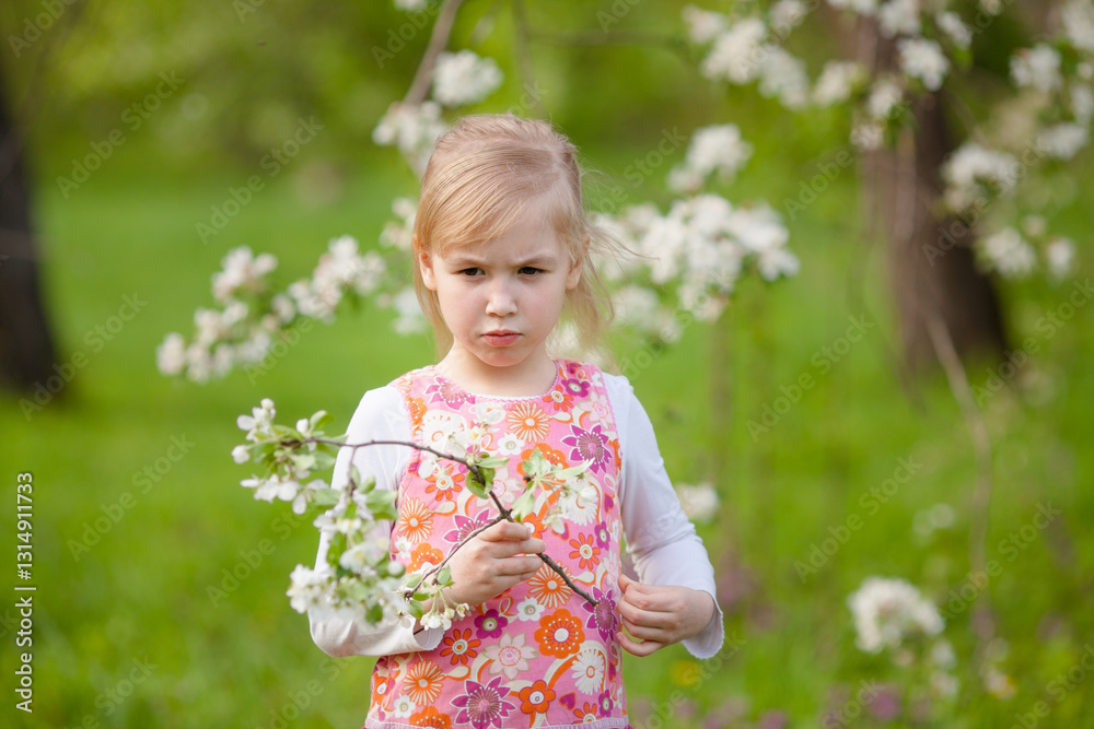 Little blonde girl looking at a blooming tree in a spring garden Little blonde girl looking at a blooming tree in a spring garden