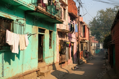 Fototapeta Naklejka Na Ścianę i Meble -  A small, crumbling apartment building with people hanging laundry on balconies, and narrow streets filled with poverty and limited infrastructure.