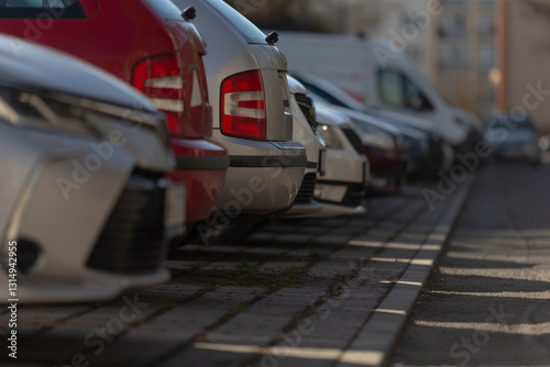 Fototapeta Naklejka Na Ścianę i Meble -  A long row of various cars is neatly parked in a spacious parking lot, showcasing the diversity of vehicles available today