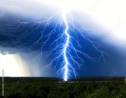 Dramatic lightning bolt striking the ground amidst a stormy sky.  A powerful image symbolizing raw energy, natures force, and the unpredictable. photo