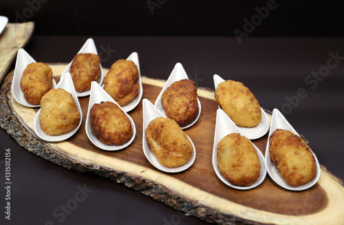aperitivos de croquetas de jamón presentadas en una bandeja de madera de árbol 
