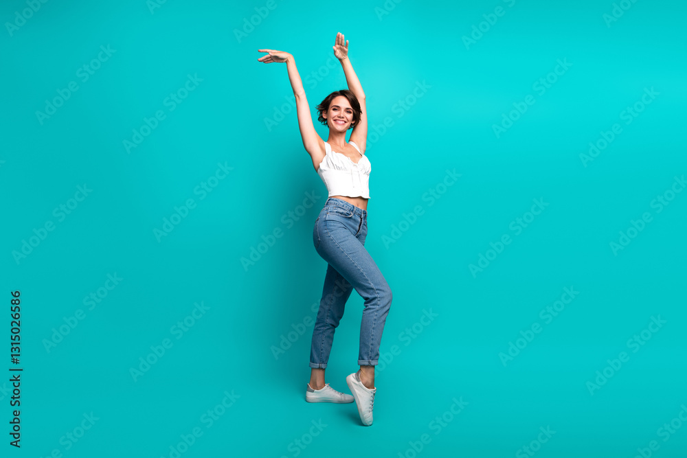 Young woman posing confidently, wearing casual jeans and top, on vibrant turquoise background, expressing joy and creativity Young woman posing confidently, wearing casual jeans and top, on vibrant turquoise background, expressing joy and creativity