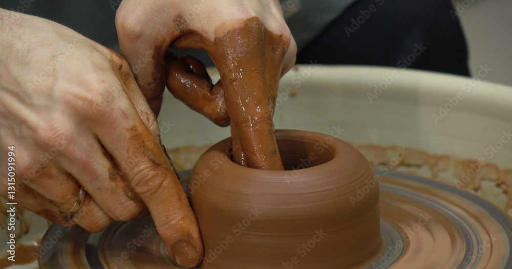 The potter's wheel. A close-up of the hands of a craftsman skillfully working with clay on a potter's wheel, giving it the shape of a clay product