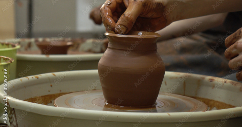 The potter's wheel. A close-up of the hands of a craftsman skillfully working with clay on a potter's wheel, giving it the shape of a clay product