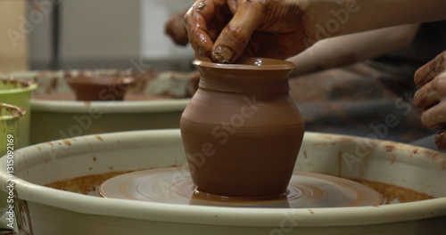 Obraz na płótnie The potter's wheel. A close-up of the hands of a craftsman skillfully working with clay on a potter's wheel, giving it the shape of a clay product w salonie