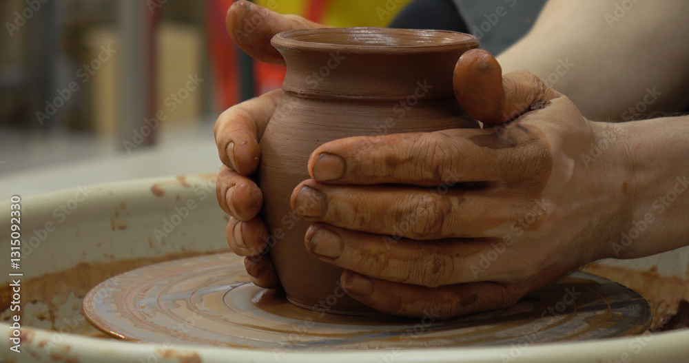 The potter's wheel. A close-up of the hands of a craftsman skillfully working with clay on a potter's wheel, giving it the shape of a clay product