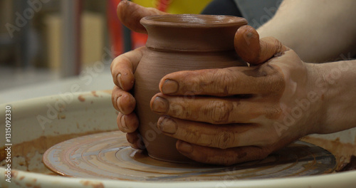 Obraz na płótnie The potter's wheel. A close-up of the hands of a craftsman skillfully working with clay on a potter's wheel, giving it the shape of a clay product w salonie