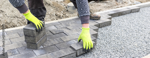 Construction worker laying paving stones on gravel for new pavement
