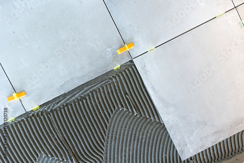 Laying ceramic tiles with tile leveling system and cement adhesive