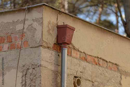 A drainpipe is securely fastened to the exterior side of a building, allowing for efficient water drainage and preventing structural damage to the structure