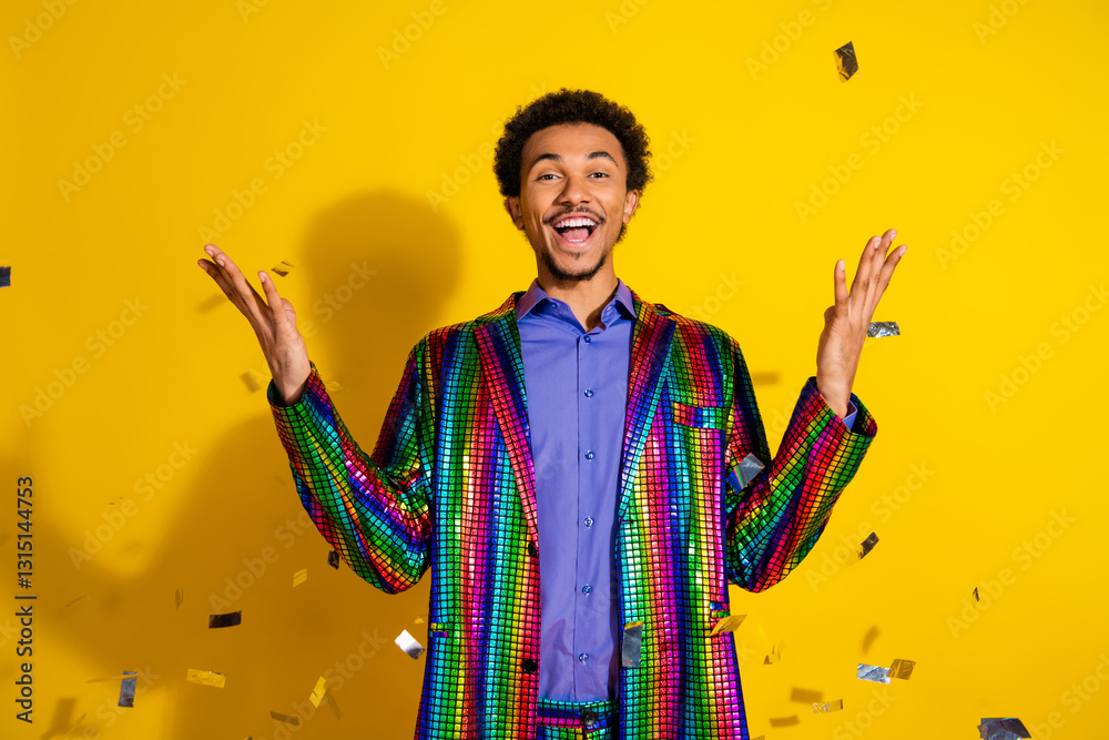 Fototapeta premium Charismatic young man in a stylish, vibrant multicolored jacket celebrates cheerfully against a lively yellow background.