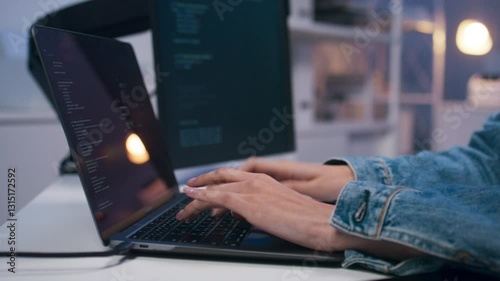 Close-up of asian female software developer hand typing on keyboard, writing prompt, code on laptop computer Multiple Screens sit at desk in office at night. Professional woman programmer working.