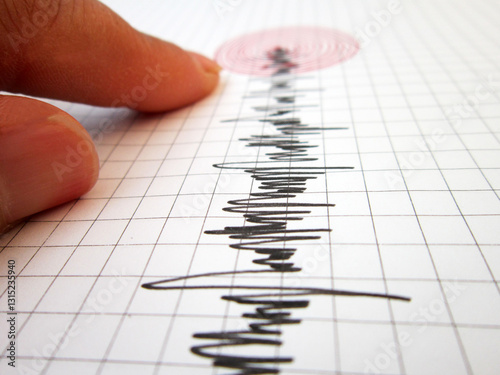 Seismograph and earthquake. A hand pointing at a seismograph recording the seismic activity of an earthquake