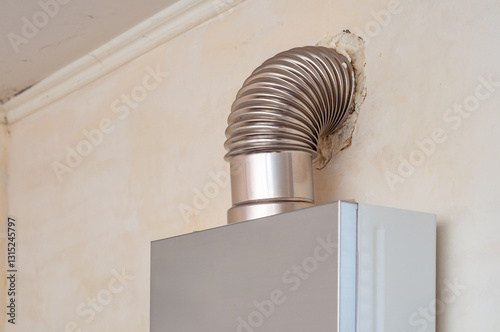 Shiny vent connects a modern water heater to an old wall with deteriorating plaster.