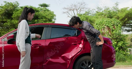 A man and a woman are engaging in a thoughtful discussion regarding a recent car accident while carefully evaluating the damage to the vehicle involved.